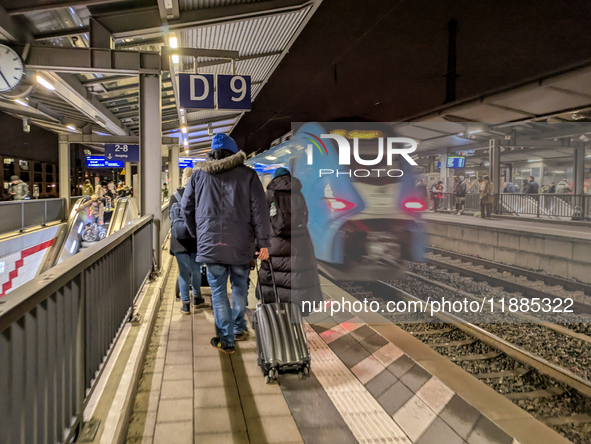 A regional train and passengers with luggage are on a platform at Munich Pasing station in Munich, Bavaria, Germany, on December 20, 2024. 