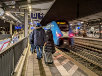 A regional train and passengers with luggage are on a platform at Munich Pasing station in Munich, Bavaria, Germany, on December 20, 2024. (