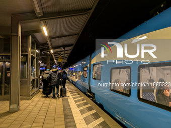 A regional train and passengers with luggage are on a platform at Munich Pasing station in Munich, Bavaria, Germany, on December 20, 2024. (