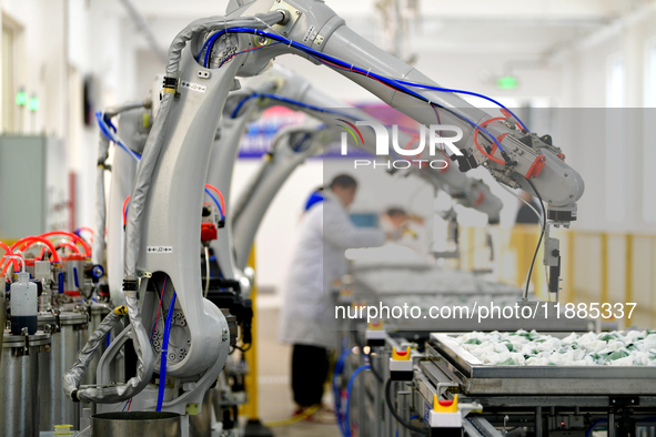 An employee operates an AI intelligent dyeing robot to produce intangible cultural heritage tie-dyeing products in a workshop in Hai'an, Jia...