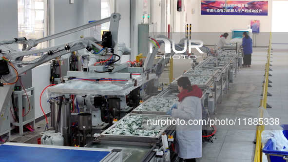 An employee operates an AI intelligent dyeing robot to produce intangible cultural heritage tie-dyeing products in a workshop in Hai'an, Jia...