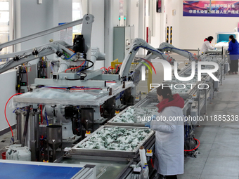 An employee operates an AI intelligent dyeing robot to produce intangible cultural heritage tie-dyeing products in a workshop in Hai'an, Jia...