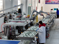 An employee operates an AI intelligent dyeing robot to produce intangible cultural heritage tie-dyeing products in a workshop in Hai'an, Jia...