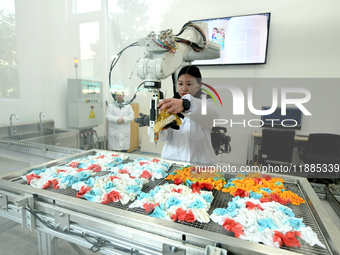 An employee operates an AI intelligent dyeing robot to produce intangible cultural heritage tie-dyeing products in a workshop in Hai'an, Jia...