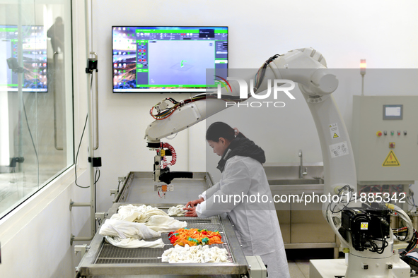 An employee operates an AI intelligent dyeing robot to produce intangible cultural heritage tie-dyeing products in a workshop in Hai'an, Jia...