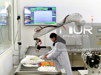 An employee operates an AI intelligent dyeing robot to produce intangible cultural heritage tie-dyeing products in a workshop in Hai'an, Jia...