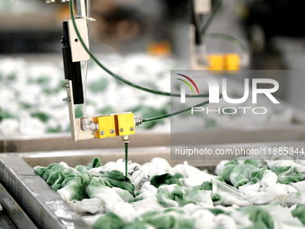 An employee operates an AI intelligent dyeing robot to produce intangible cultural heritage tie-dyeing products in a workshop in Hai'an, Jia...