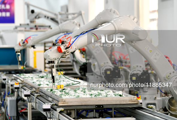 An employee operates an AI intelligent dyeing robot to produce intangible cultural heritage tie-dyeing products in a workshop in Hai'an, Jia...