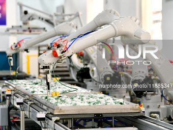 An employee operates an AI intelligent dyeing robot to produce intangible cultural heritage tie-dyeing products in a workshop in Hai'an, Jia...