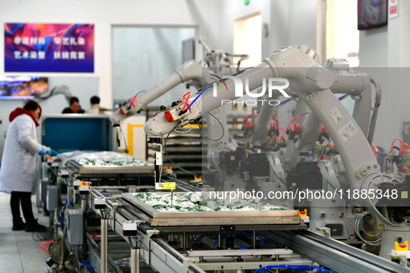 An employee operates an AI intelligent dyeing robot to produce intangible cultural heritage tie-dyeing products in a workshop in Hai'an, Jia...