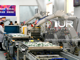 An employee operates an AI intelligent dyeing robot to produce intangible cultural heritage tie-dyeing products in a workshop in Hai'an, Jia...