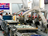 An employee operates an AI intelligent dyeing robot to produce intangible cultural heritage tie-dyeing products in a workshop in Hai'an, Jia...