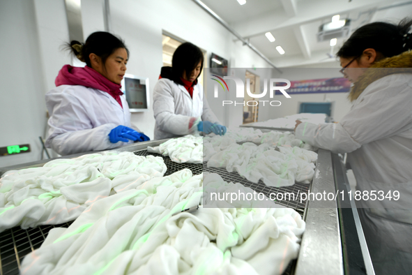 An employee operates an AI intelligent dyeing robot to produce intangible cultural heritage tie-dyeing products in a workshop in Hai'an, Jia...