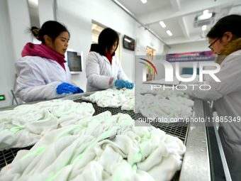 An employee operates an AI intelligent dyeing robot to produce intangible cultural heritage tie-dyeing products in a workshop in Hai'an, Jia...