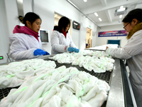 An employee operates an AI intelligent dyeing robot to produce intangible cultural heritage tie-dyeing products in a workshop in Hai'an, Jia...