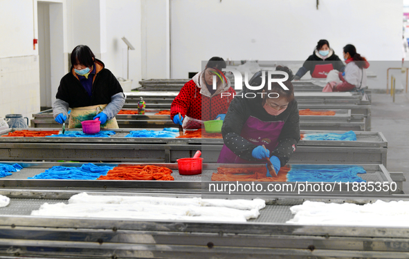 An employee operates an AI intelligent dyeing robot to produce intangible cultural heritage tie-dyeing products in a workshop in Hai'an, Jia...