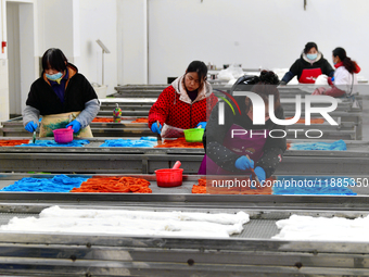 An employee operates an AI intelligent dyeing robot to produce intangible cultural heritage tie-dyeing products in a workshop in Hai'an, Jia...