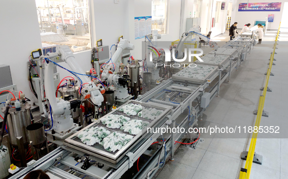 An employee operates an AI intelligent dyeing robot to produce intangible cultural heritage tie-dyeing products in a workshop in Hai'an, Jia...