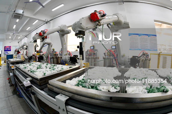 An employee operates an AI intelligent dyeing robot to produce intangible cultural heritage tie-dyeing products in a workshop in Hai'an, Jia...