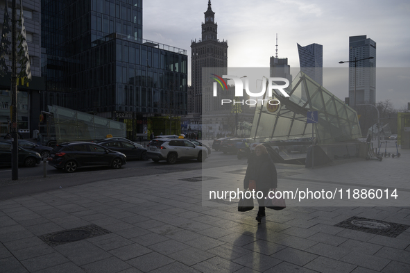 A woman walks on the sidewalk with the Palace of Culture and Science in the background in Warsaw, Poland, on December 21, 2024. 