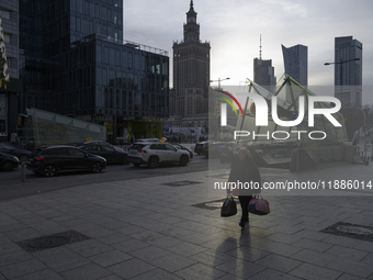 A woman walks on the sidewalk with the Palace of Culture and Science in the background in Warsaw, Poland, on December 21, 2024. (