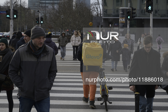 A Glovo courier pushes his bicycle at a road crossing in Warsaw, Poland, on December 21, 2024. 