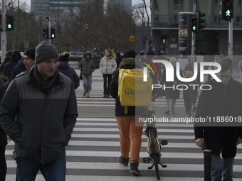 A Glovo courier pushes his bicycle at a road crossing in Warsaw, Poland, on December 21, 2024. (