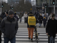 A Glovo courier pushes his bicycle at a road crossing in Warsaw, Poland, on December 21, 2024. (