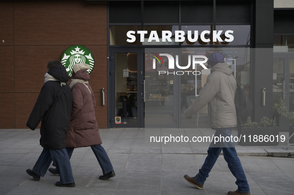 People walk past a Starbucks coffee shop in Warsaw, Poland, on December 21, 2024. 