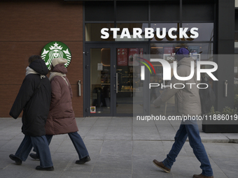 People walk past a Starbucks coffee shop in Warsaw, Poland, on December 21, 2024. (