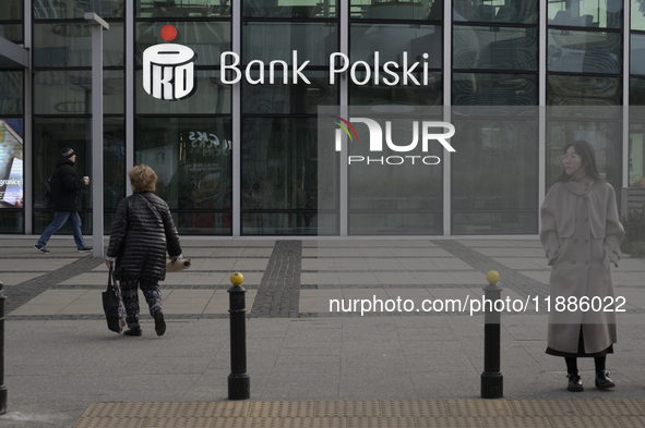 People walk past a PKO Bank Polski sign in Warsaw, Poland, on December 21, 2024. 