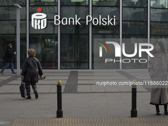 People walk past a PKO Bank Polski sign in Warsaw, Poland, on December 21, 2024. (