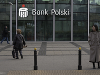 People walk past a PKO Bank Polski sign in Warsaw, Poland, on December 21, 2024. (