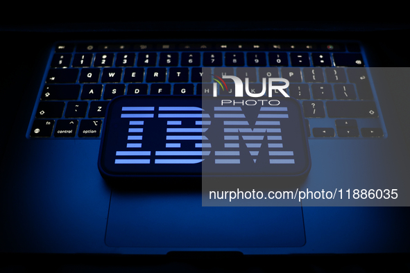 A laptop keyboard and IBM logo displayed on a smartphone are seen in this illustration photo taken in Krakow, Poland on December 21, 2024. 