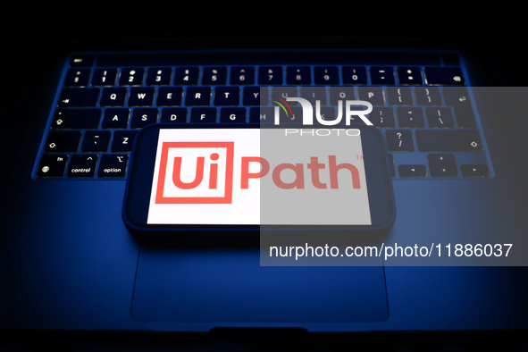 A laptop keyboard and UiPath logo displayed on a smartphone are seen in this illustration photo taken in Krakow, Poland on December 21, 2024...