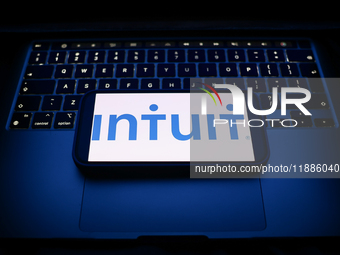 A laptop keyboard and Intuit logo displayed on a smartphone are seen in this illustration photo taken in Krakow, Poland on December 21, 2024...