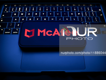 A laptop keyboard and McAfee logo displayed on a smartphone are seen in this illustration photo taken in Krakow, Poland on December 21, 2024...