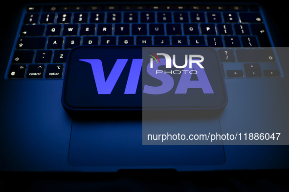 A laptop keyboard and Visa logo displayed on a smartphone are seen in this illustration photo taken in Krakow, Poland on December 21, 2024. 