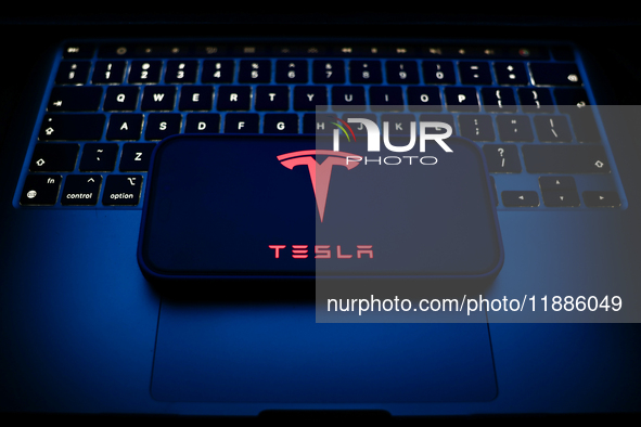 A laptop keyboard and Tesla logo displayed on a smartphone are seen in this illustration photo taken in Krakow, Poland on December 21, 2024....