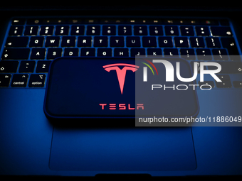 A laptop keyboard and Tesla logo displayed on a smartphone are seen in this illustration photo taken in Krakow, Poland on December 21, 2024....