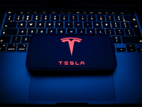 A laptop keyboard and Tesla logo displayed on a smartphone are seen in this illustration photo taken in Krakow, Poland on December 21, 2024....