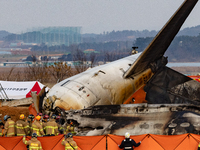 Fire authorities search for the missing and recover the deceased at the site of an accident near Muan International Airport in Jeollanam-do,...