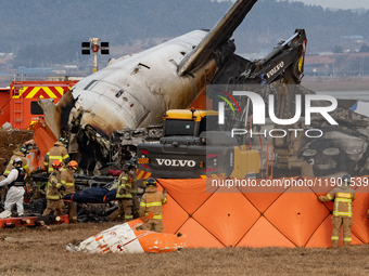 Fire authorities search for the missing and recover the deceased at the site of an accident near Muan International Airport in Jeollanam-do,...