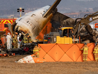 Fire authorities search for the missing and recover the deceased at the site of an accident near Muan International Airport in Jeollanam-do,...