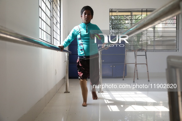 A boy attempts to walk using a railing for support after acquiring a new prosthetic limb inside the Rehabilitation & Research Centre, a unit...