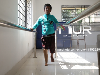 A boy attempts to walk using a railing for support after acquiring a new prosthetic limb inside the Rehabilitation & Research Centre, a unit...