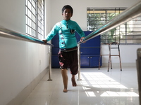 A boy attempts to walk using a railing for support after acquiring a new prosthetic limb inside the Rehabilitation & Research Centre, a unit...