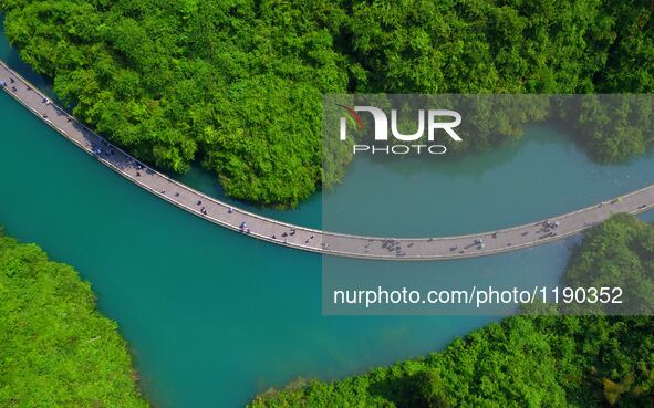 Tourists walk on a 500-meter-long plank road built over the river in Xuan'en County, central China's Hubei Province, May 1, 2016.