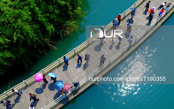 Tourists walk on a 500-meter-long plank road built over the river in Xuan'en County, central China's Hubei Province, May 1, 2016.