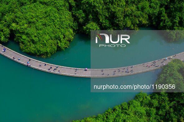 Tourists walk on a 500-meter-long plank road built over the river in Xuan'en County, central China's Hubei Province, May 1, 2016.